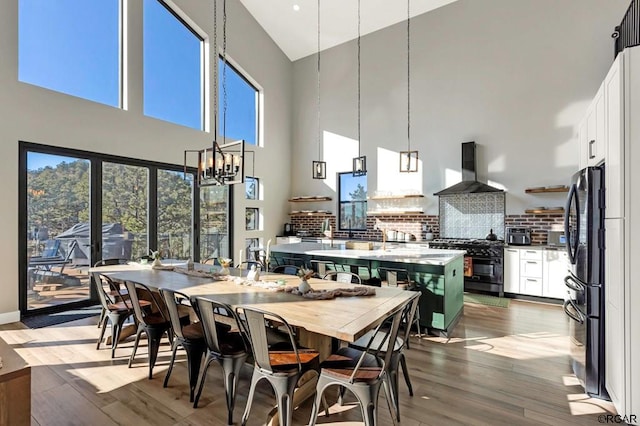 dining space with a notable chandelier, light hardwood / wood-style floors, and a high ceiling