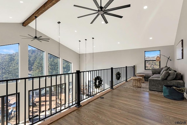 living area featuring beamed ceiling, wood-type flooring, high vaulted ceiling, and ceiling fan