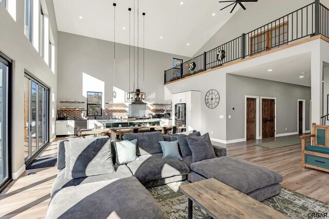 living room with light hardwood / wood-style flooring, ceiling fan, and a high ceiling