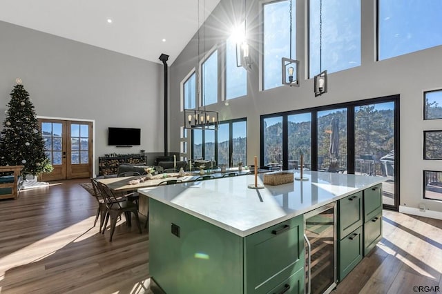 kitchen featuring a high ceiling, pendant lighting, green cabinets, and beverage cooler