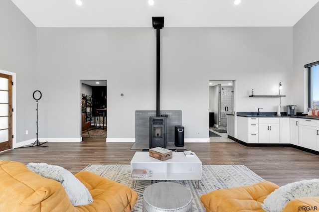 living room featuring a wood stove, dark hardwood / wood-style flooring, and a towering ceiling