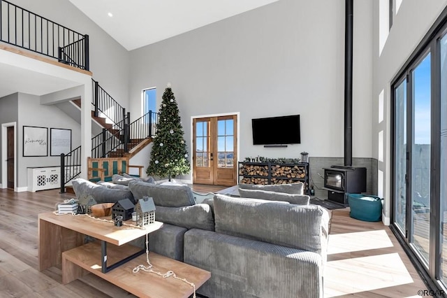 living room with hardwood / wood-style floors, a towering ceiling, plenty of natural light, and french doors