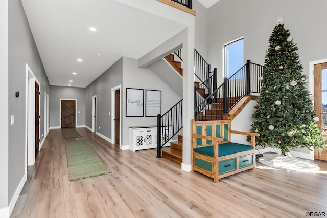 foyer entrance with a towering ceiling and light hardwood / wood-style flooring