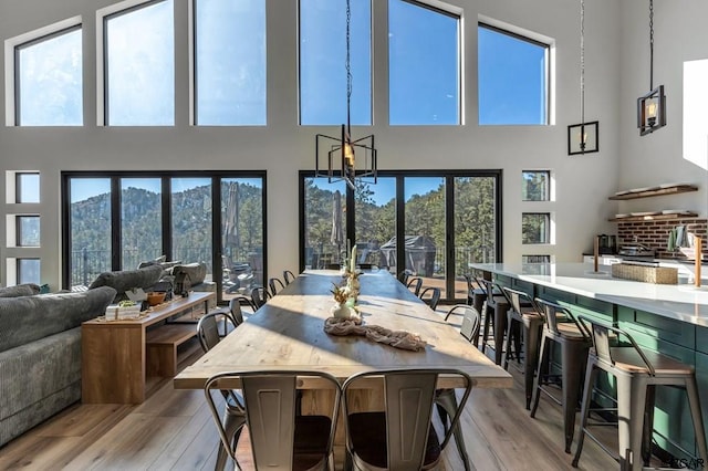 dining area with a towering ceiling, a mountain view, and light wood-type flooring