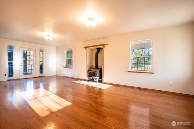 empty room with wood-type flooring and a wood stove