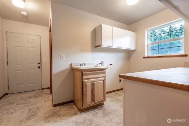 laundry room featuring hookup for a washing machine, light tile flooring, and cabinets