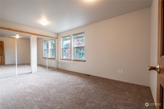 unfurnished bedroom featuring multiple closets and carpet floors