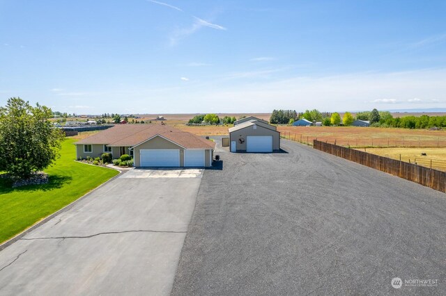 ranch-style home with a rural view, a front yard, and a garage