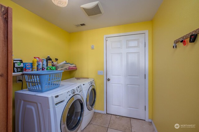 clothes washing area with independent washer and dryer and light tile patterned floors