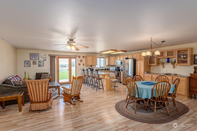 dining room with ceiling fan with notable chandelier, light hardwood / wood-style flooring, and sink