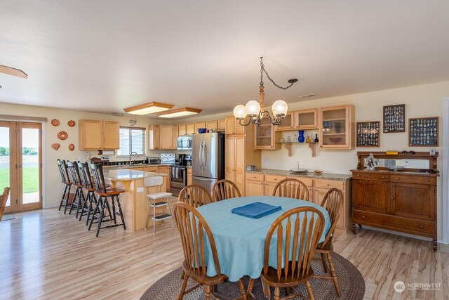 dining space with plenty of natural light, light hardwood / wood-style floors, sink, and a chandelier