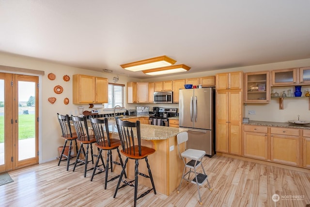 kitchen with a breakfast bar, light wood-type flooring, plenty of natural light, and appliances with stainless steel finishes