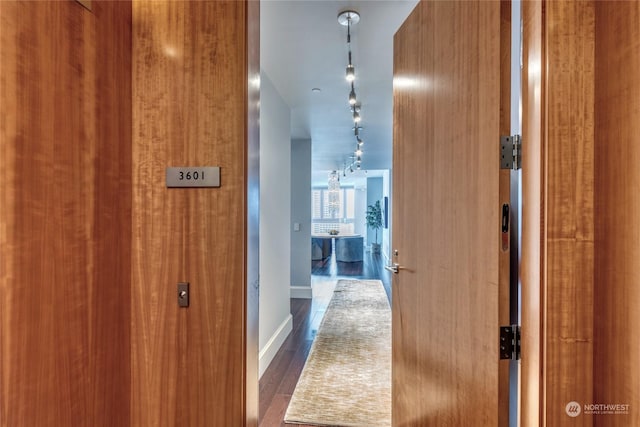 hall with rail lighting and dark hardwood / wood-style flooring