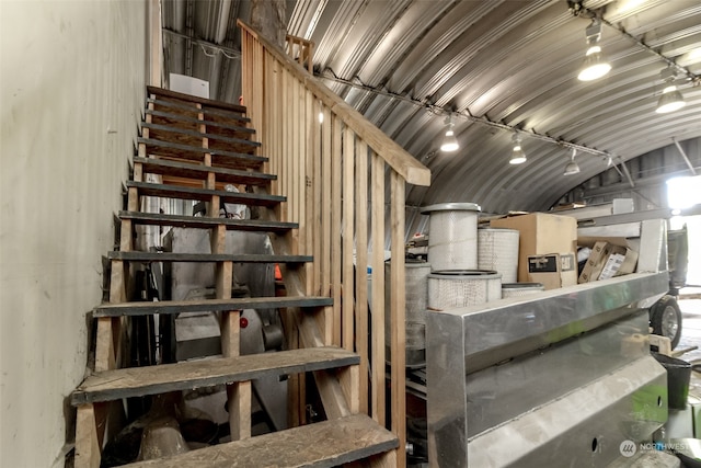 staircase with track lighting and lofted ceiling