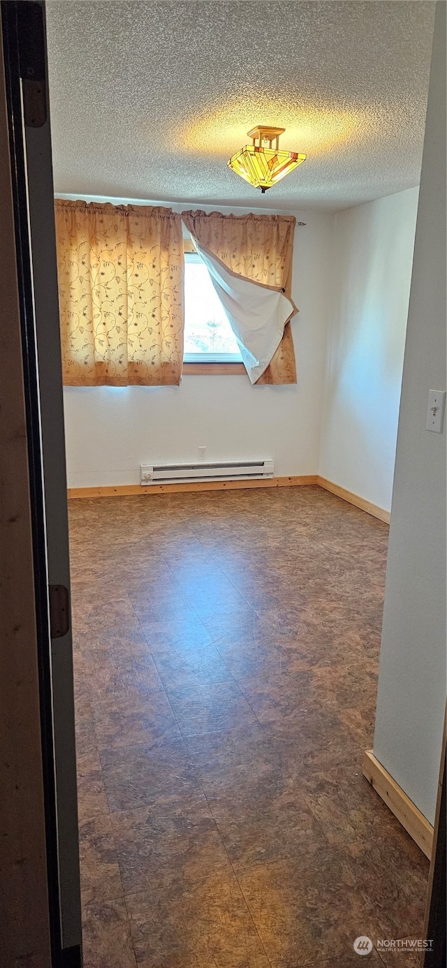 unfurnished room featuring a baseboard heating unit and a textured ceiling