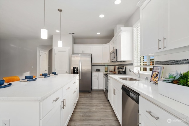 kitchen with hanging light fixtures, sink, white cabinets, decorative backsplash, and stainless steel appliances