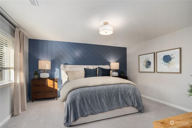 bedroom featuring light carpet and wooden walls