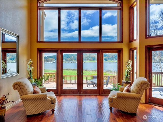 doorway with a water view, a high ceiling, hardwood / wood-style floors, and plenty of natural light