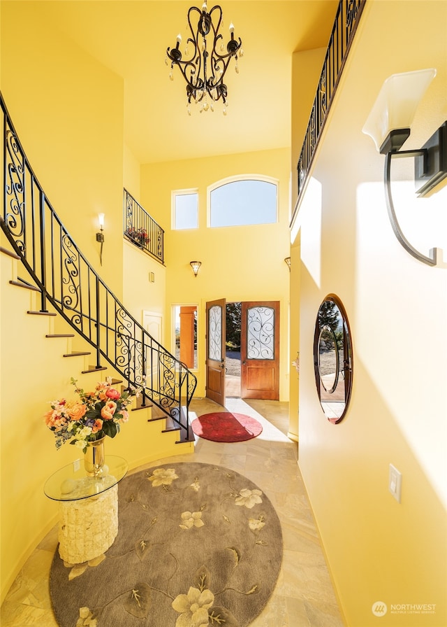 entrance foyer with an inviting chandelier, a towering ceiling, and light tile flooring