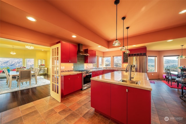 kitchen featuring an island with sink, dark tile flooring, stainless steel appliances, and sink