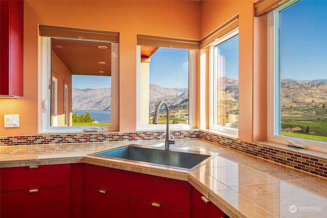 kitchen with sink, a mountain view, tile countertops, and tasteful backsplash