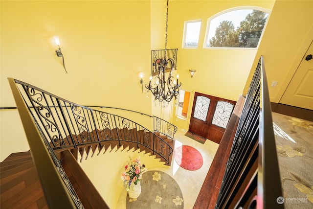 staircase featuring a notable chandelier, a high ceiling, and french doors