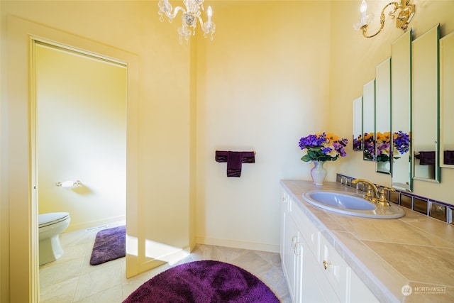 bathroom with an inviting chandelier, toilet, tile floors, and large vanity