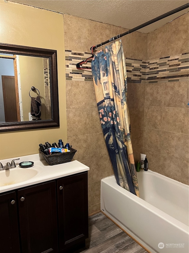 bathroom with a textured ceiling, vanity, hardwood / wood-style floors, and shower / bath combo with shower curtain