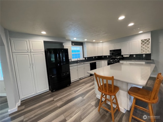 653 Sunset Ave NE, Ocean Shores, WA 98569 - kitchen with black appliances, a kitchen breakfast bar, white cabinets, tasteful backsplash, and dark hardwood / wood-style flooring