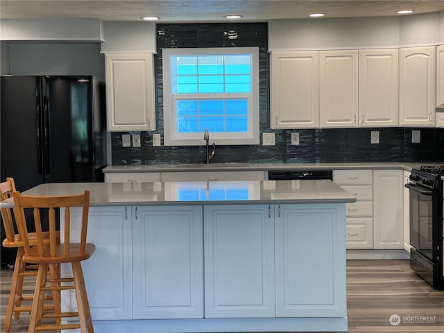 653 Sunset Ave NE, Ocean Shores, WA 98569 - kitchen with white cabinets, black range with gas cooktop, tasteful backsplash, and wood-type flooring