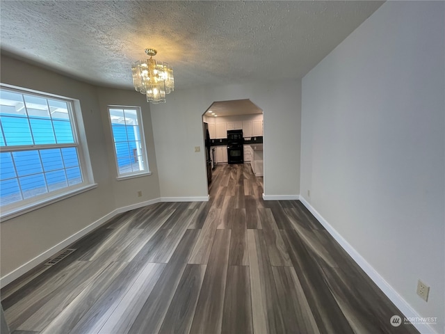 653 Sunset Ave NE, Ocean Shores, WA 98569 - unfurnished room featuring an inviting chandelier, a textured ceiling, and dark hardwood / wood-style floors