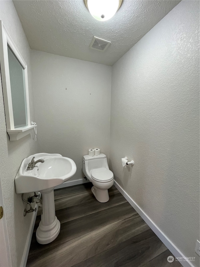 653 Sunset Ave NE, Ocean Shores, WA 98569 - bathroom with a textured ceiling, toilet, and wood-type flooring