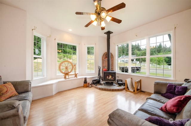 living room featuring a wood stove, ceiling fan, and light wood-type flooring