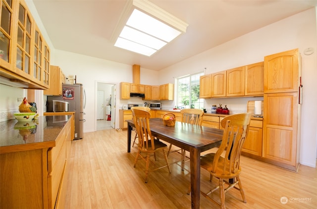 dining room with a skylight and light hardwood / wood-style floors