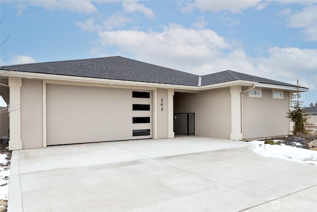 view of front of home with driveway, a shingled roof, a garage, and stucco siding