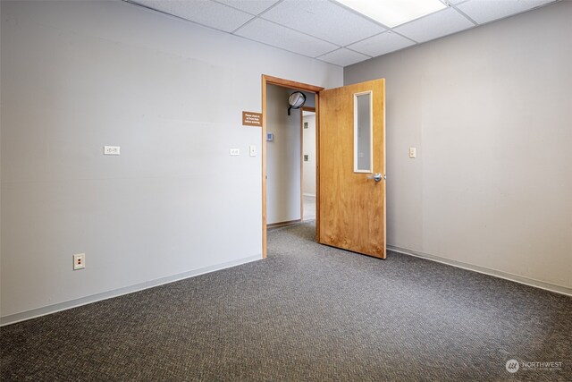 empty room featuring a drop ceiling and dark colored carpet