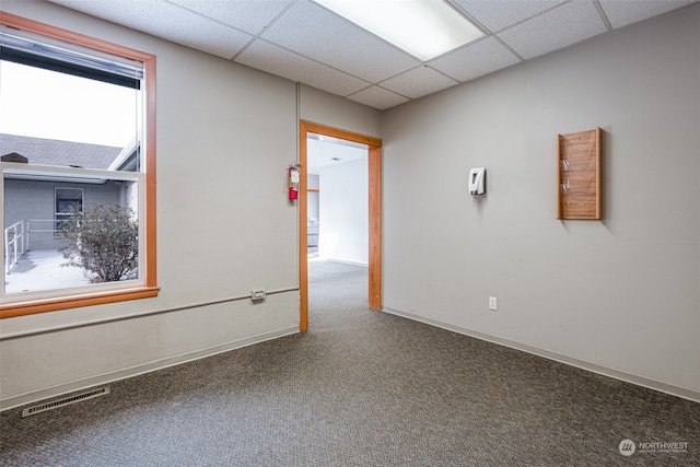 carpeted spare room featuring a drop ceiling