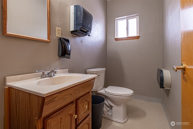 bathroom with toilet, large vanity, and tile floors