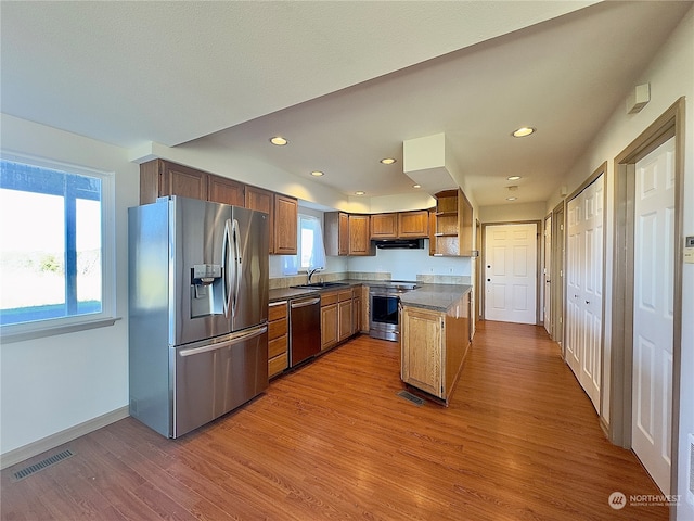 kitchen featuring extractor fan, hardwood / wood-style floors, stainless steel appliances, and sink