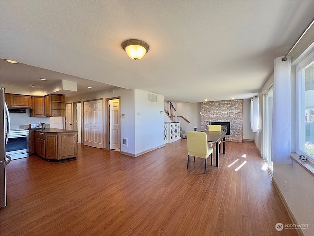 dining area with dark hardwood / wood-style floors and a brick fireplace