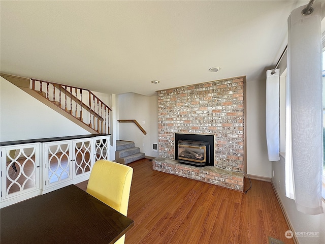 unfurnished living room featuring a brick fireplace, brick wall, and dark hardwood / wood-style floors