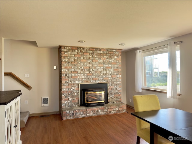 unfurnished living room with a brick fireplace, brick wall, and hardwood / wood-style flooring