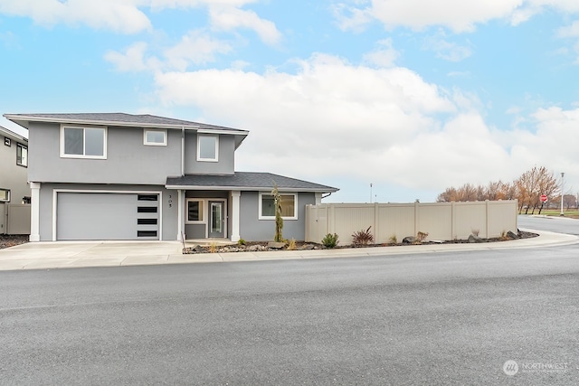 view of front of home featuring driveway, a garage, fence, and stucco siding