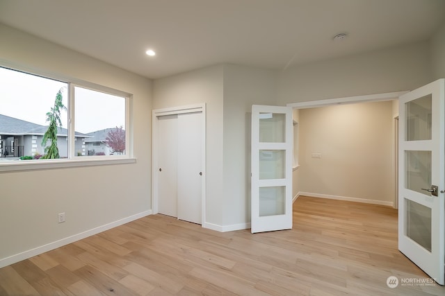 unfurnished bedroom with french doors, light wood finished floors, recessed lighting, a closet, and baseboards