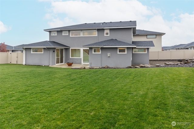 rear view of property with a patio, a yard, fence, and stucco siding