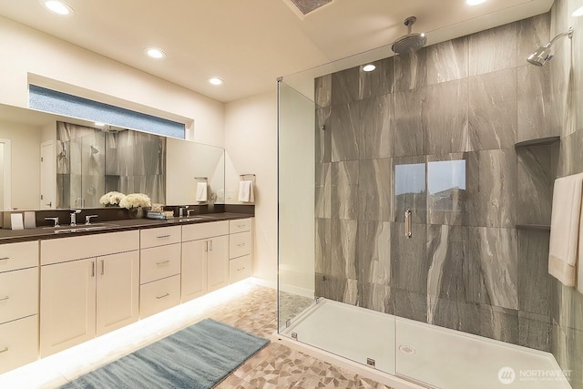 bathroom featuring double vanity, a shower stall, visible vents, and a sink