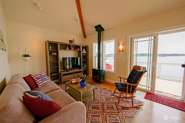 living room featuring light wood-style floors, a wood stove, baseboards, and lofted ceiling
