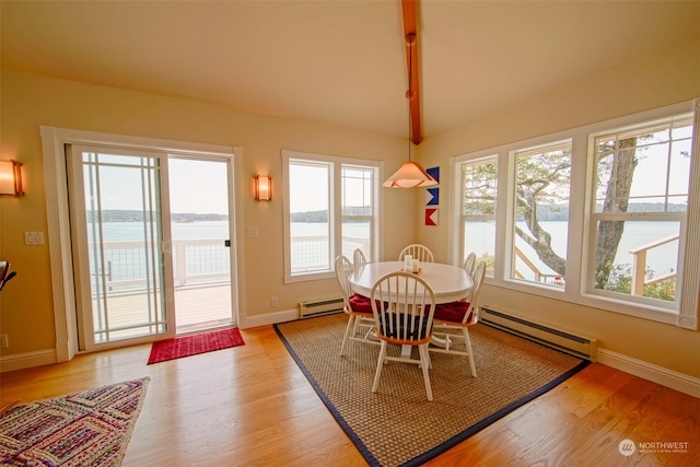 dining area with a water view, light wood-type flooring, vaulted ceiling, and baseboard heating