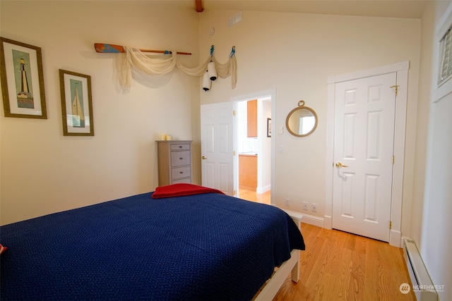 bedroom with baseboards, light wood finished floors, a baseboard heating unit, and lofted ceiling