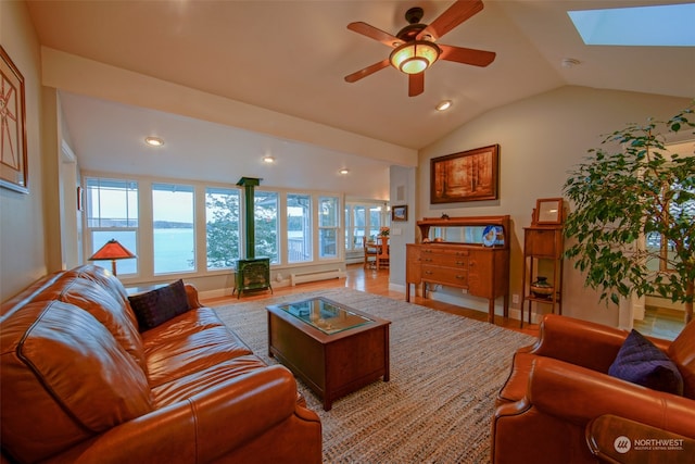 living room featuring a wood stove, a ceiling fan, recessed lighting, light wood finished floors, and lofted ceiling with skylight